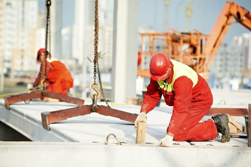 Two Gladstone Concreters workers lay down concrete beams for a building